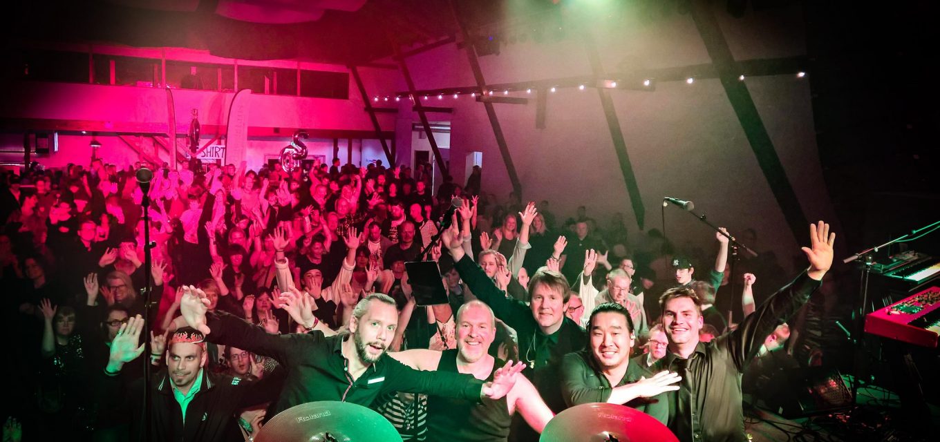 Publik och band i rött och grönt ljus från scenen under Skånerock