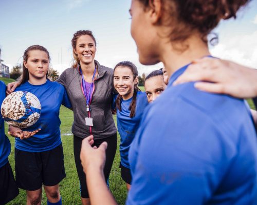 Kvinnlig fotbollstränare med tjejlag i ring