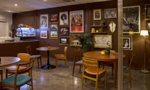 cafemiljö med runda bord en tavelvägg med musik och arkivbilder en disk med mat